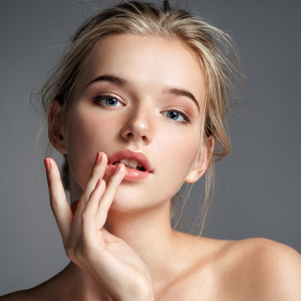 Image with beautiful blonde girl touching her lips on grey background. Beauty & Skin care concept