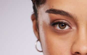 Eye, vision and beauty with contact lens and black woman, care for eyes and cosmetics with closeup on studio background. Microblading, eyebrow and lashes, face and skin in portrait with mockup space